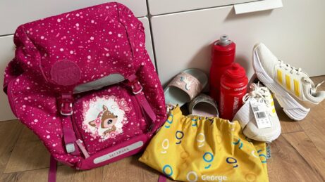 Detské tenisky, papuče a školská taška pri príprave na nový školský rok